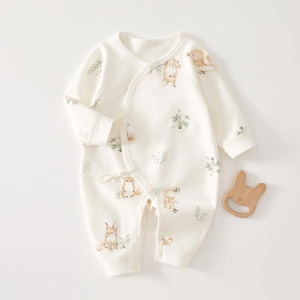 Detail of soft cotton newborn romper featuring tie-front closure and cute fox prints