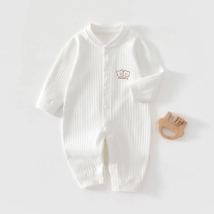 Detail eines cremefarbenen Baby-Bodys mit Bärenstickerei und praktischer Knopfleiste