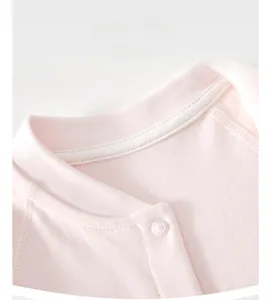 Close-up of pink cotton baby bodysuit neckline with snap button and white piping detail