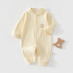 Detail eines weichen gelben Baby-Stramplers mit Bärenstickerei und Druckknopfleiste