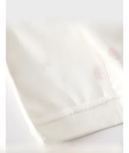 Close-up of baby romper fabric showing dense stitching and soft pink polka dots