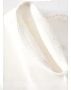 Close-up of soft cotton baby romper sleeve with pink heart patterns and flat seams