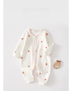 Close-up of baby romper with strawberry print and red wavy trim on soft white cotton