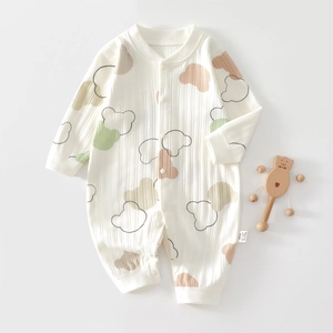 Detail of soft ribbed cotton baby romper with colorful bear print and wood rattle