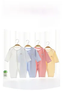 Close-up of four breathable cotton baby rompers with rainbow embroidery on hangers