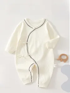 Close-up of baby romper with side ties and delicate blue embroidered wave trim details