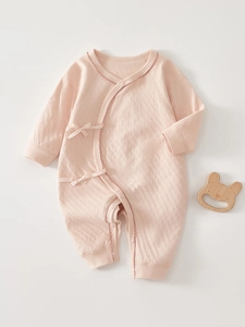 Detailed macro view of pink long-sleeved baby bodysuit with textured diamond pattern