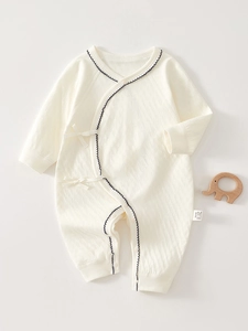 Detail of baby cotton romper featuring side-tie closure and delicate blue wave embroidery