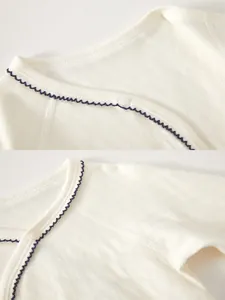 Detail of baby cotton onesie featuring soft knit texture and blue wavy piped neckline
