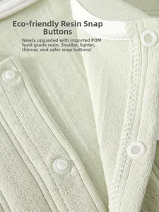 Detailaufnahme der umweltfreundlichen POM-Harz-Druckknöpfe auf grünem Baby-Body aus Baumwolle