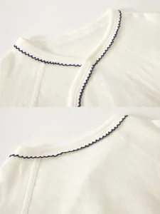 Detail of baby cotton onesie with wavy blue lace trim and side button closure