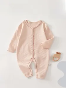 Close-up of pink cotton baby romper featuring diamond texture and scalloped lace edges
