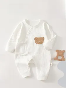 Detail of white cotton newborn bodysuit featuring waffle knit and side-tie kimono closure