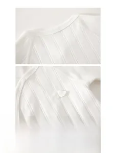 Detail of white cotton baby bodysuit showing ribbed fabric and embroidered bear head