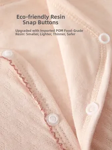 Detailed close-up of safe food-grade resin snap buttons on pink cotton baby romper fabric