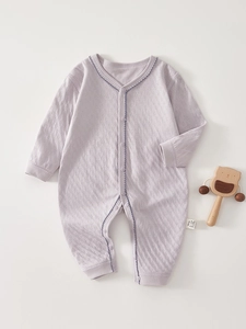 Close-up of lilac waffle knit cotton baby romper with wave stitch trim and wood bear toy