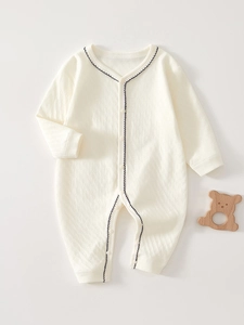 Detail of baby romper featuring diamond jacquard cotton fabric and wavy lace trim