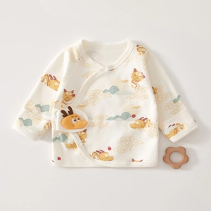 Détail de haut croisé pour nouveau-né avec broderie dragon et peluche dragon 3D
