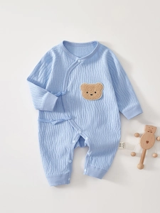 Detailed macro shot of light blue cotton baby romper with waffle texture and bear patch