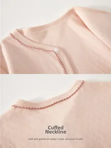 Detail of baby pink cotton bodysuit neckline with breathable texture and scalloped edges