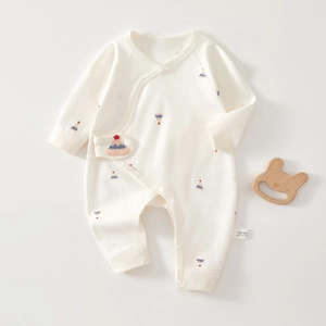 Macro detail of cream baby cotton romper featuring colorful mountain print and snap buttons