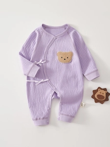 Detail of lavender cotton infant romper with waffle texture and brown teddy bear patch