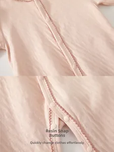 Detail view of pink baby romper showing soft jacquard cotton texture and resin snap buttons