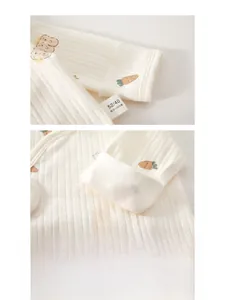 Détail d'une manche de bébé en coton côtelé avec motif ours et étiquette 100% pur coton