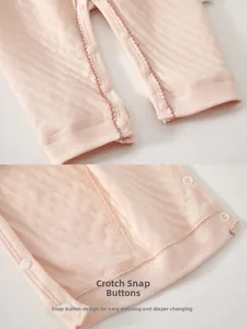 Close-up of snap button closure on light pink waffle knit cotton baby romper for easy changes