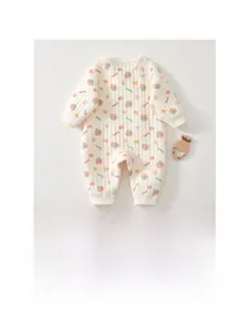 Detail of baby romper featuring red tomato prints and ribbed cuffs on cream knit fabric
