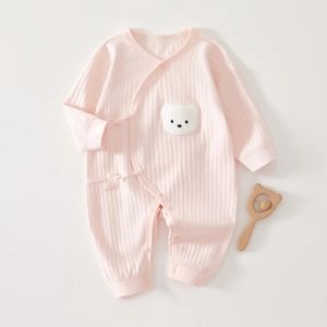 Détail d'une grenouillère en coton côtelé rose pour bébé avec broderie ours et nœud