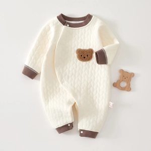 Dettaglio della tutina trapuntata color crema per neonato con toppa a forma di orso