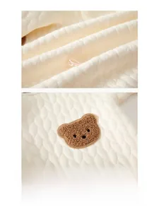 Vista dettagliata del tessuto di cotone trapuntato beige con ricamo di orsetto