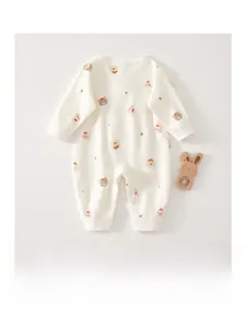 Detail of baby cotton romper featuring cute bear and rabbit cartoon prints on creamy fabric