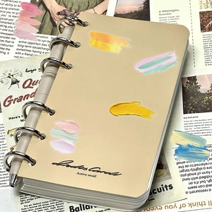 Detail of artistic binder notebook with Active Recall logo and sleek metal pen on newspapers