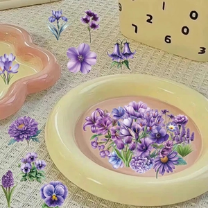 Detail view of assorted purple floral PET stickers for scrapbooking on a checkered surface