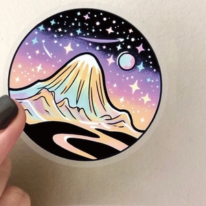 Macro shot of a holographic magic witch sticker showing mountain and starry sky details