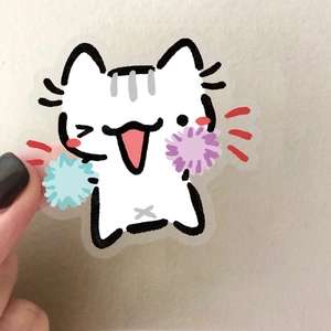 Gros plan d'un autocollant chaton drôle avec des pompons sur un fond transparent