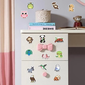 Variété d'autocollants animaux mignons décorant un tiroir blanc et un mur dans une chambre