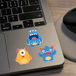 Close-up of cute cartoon monster stickers on a grey laptop palm rest for DIY decoration