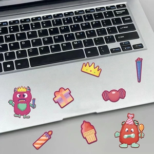 Close-up of colorful cartoon monster stickers applied on a silver laptop surface