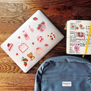 Detailed aesthetic strawberry stickers on a laptop and notebook for DIY journaling