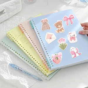 Autocollants roses mignons de dessins animés sur un carnet à spirales bleu clair