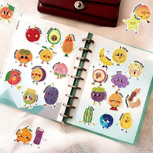 Detail of cartoon fruit stickers with English names on a notebook page for scrapbooking