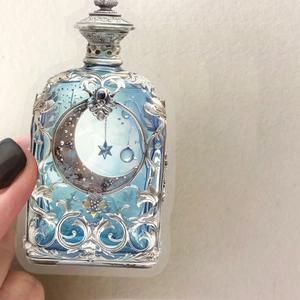 Close-up of light blue PET moon bottle sticker with silver embossed floral patterns