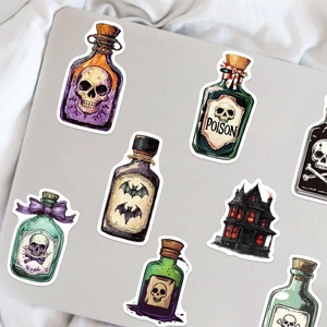 Gothic Halloween potion bottle and haunted house stickers on a laptop surface