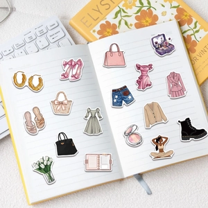Macro view of fashion lifestyle stickers featuring bags and shoes on an open notebook