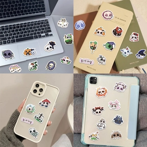 Detailed application of waterproof cartoon skull stickers on a laptop and notebook
