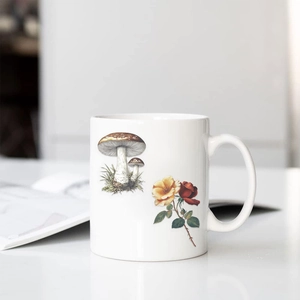 Detail of a white ceramic mug featuring vintage botanical mushroom and rose illustrations
