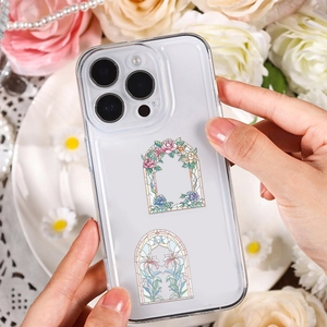 Coque transparente imprimée d'arches florales tenue en main avec fond élégant de roses